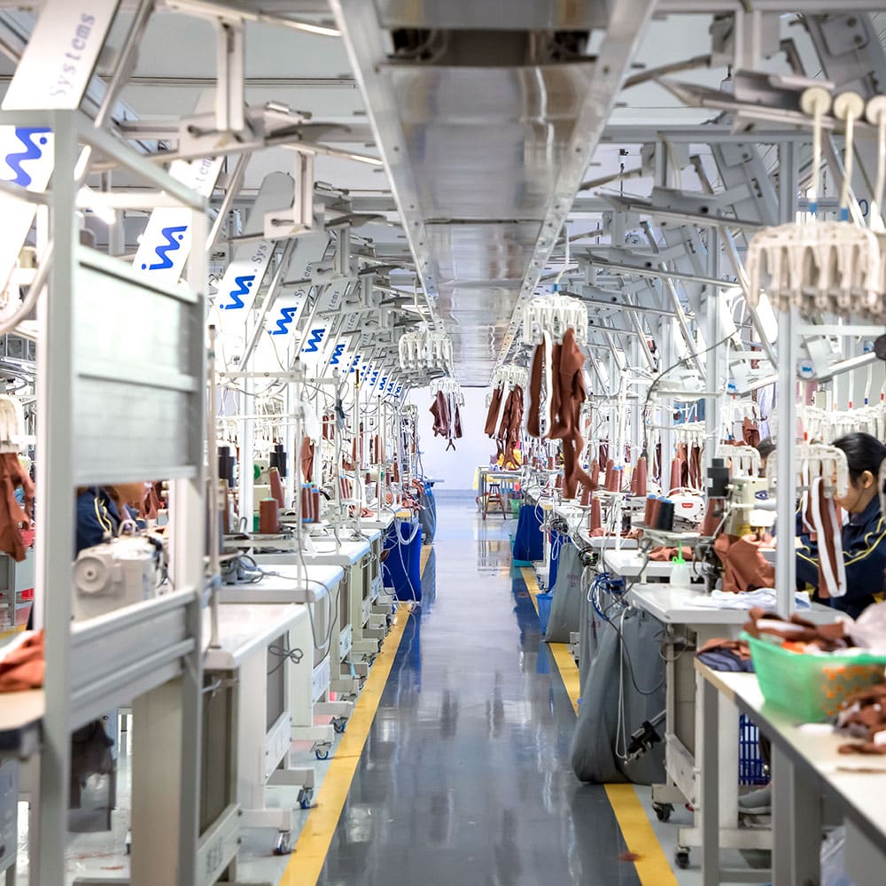 Modern garment assembly line in a China-based factory featuring INA Systems automated transport for high-efficiency seamless activewear production.