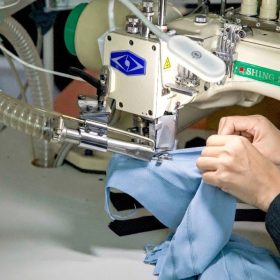 Close-up view of precision stitching details on light blue high-stretch activewear fabric, demonstrating the manufacturing craftsmanship at Maes Group facility.
