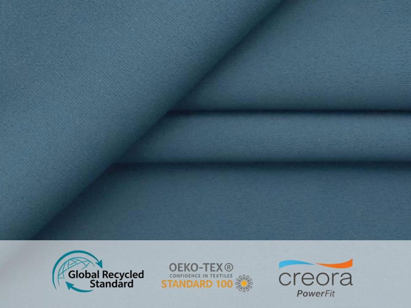 High-performance blue technical fabric with GRS, OEKO-TEX Standard 100, and Creora PowerFit logos, highlighting sustainable activewear sourcing.